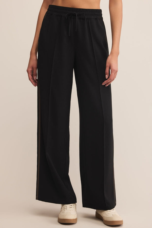 Black wide-leg pants worn by a person on a beige background