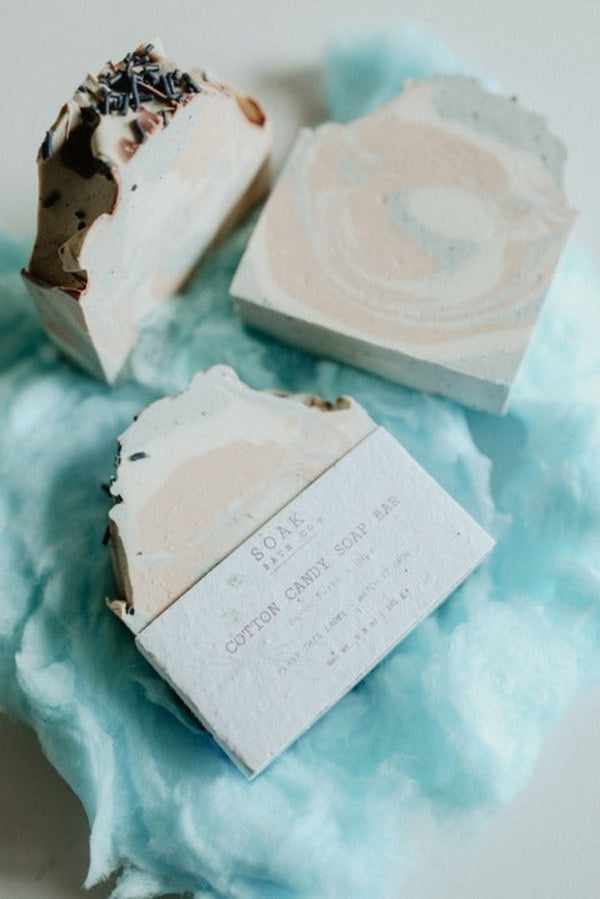 Three soap bars with marbled designs on a blue fabric background