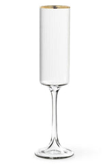 Clear glass flute with ribbed design and gold rim on a white background