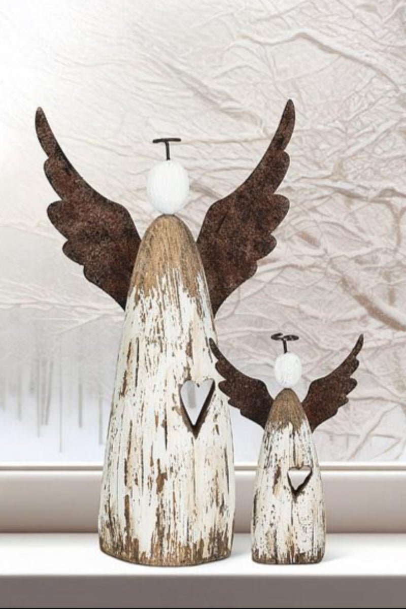 Two wooden angel figurines with wings against a window with a snowy scene.