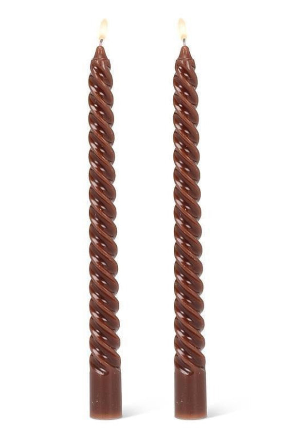 Two twisted brown candles on a white background