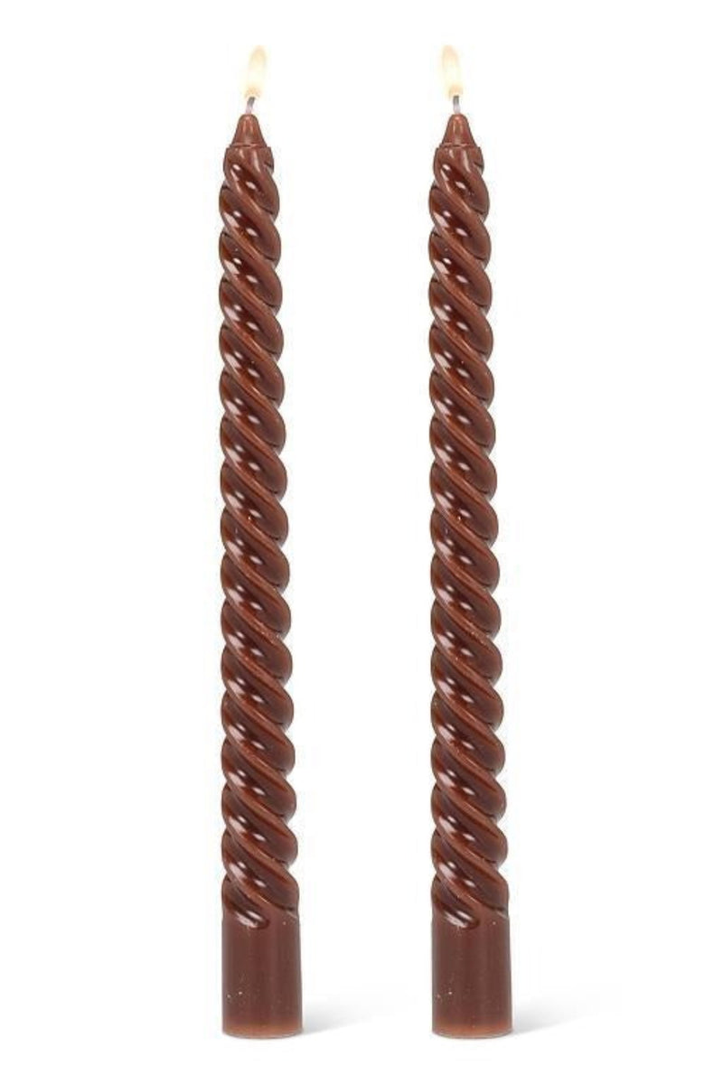 Two twisted brown candles on a white background