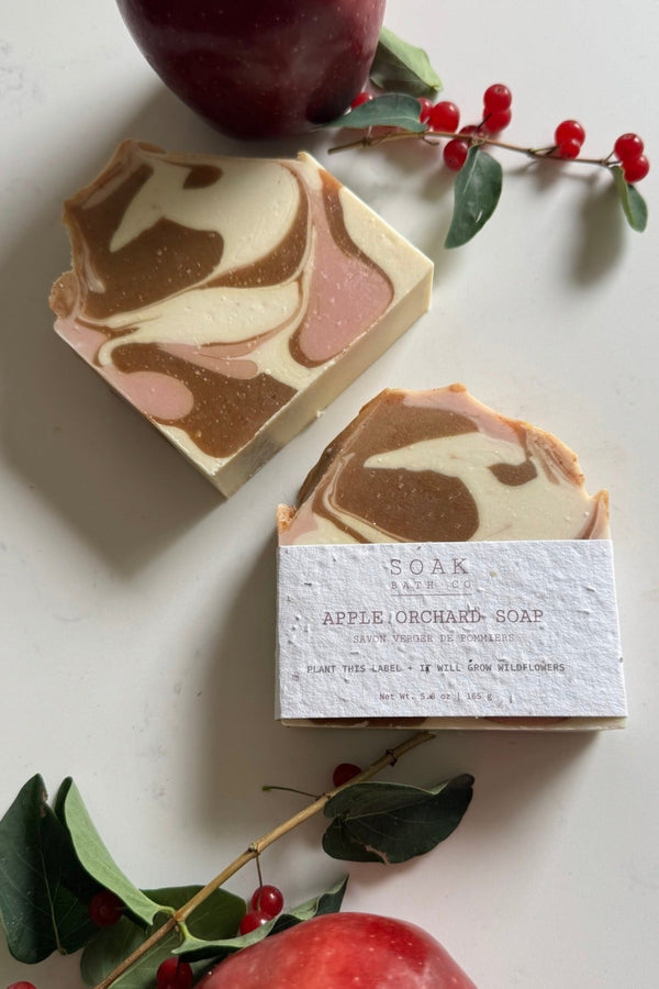 Marbled soap bar with a label on a white surface with apples and leaves.