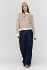 Woman wearing a striped sweater and dark pants on a white background
