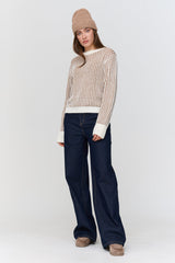 Person wearing a striped sweater, navy pants, and a beanie on a white background