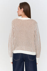 Woman wearing a patterned sweater and dark jeans on a white background