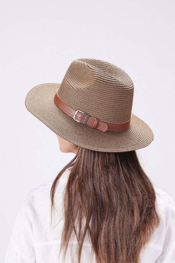 Person wearing a brown straw hat with a leather band on a white background