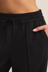 Black pants with drawstring waist on a neutral background