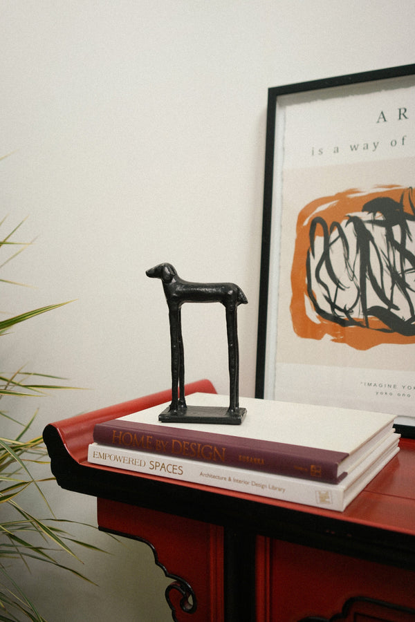 Small black sculpture on books with a framed print in the background