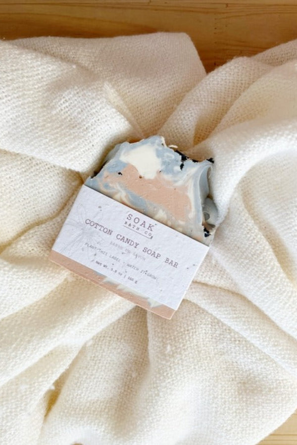 Cotton candy soap bar with packaging on a textured white fabric background