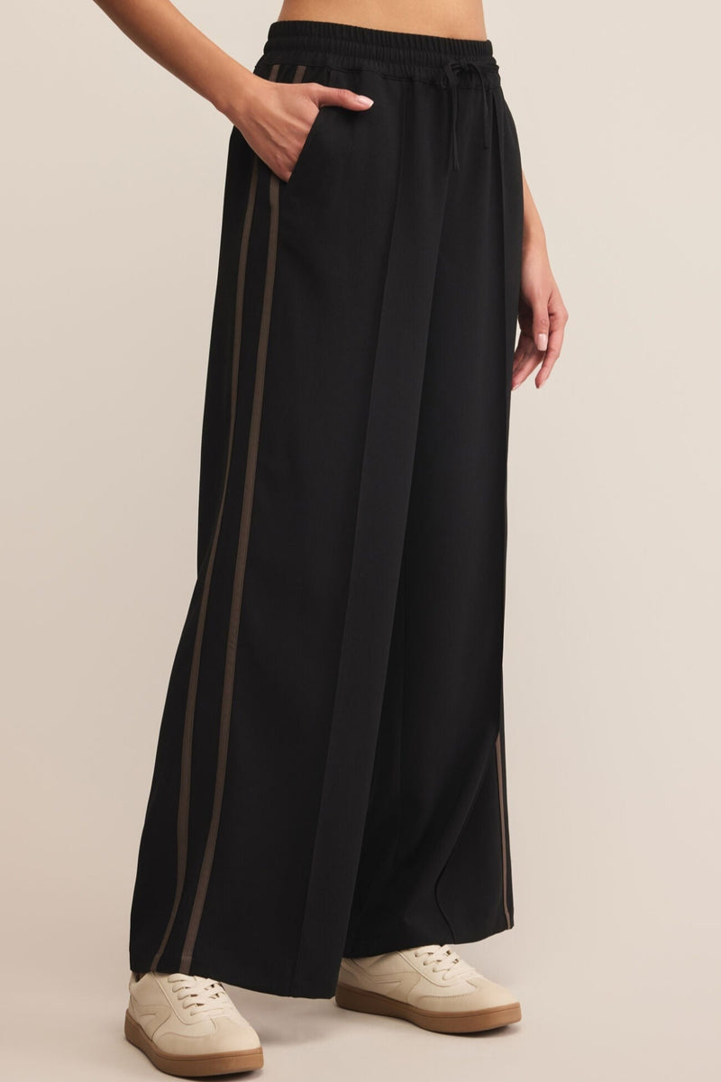 Black wide-leg pants worn by a person on a beige background
