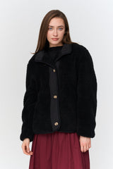 Woman wearing a black jacket with brown buttons on a white background