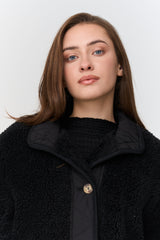 Woman wearing a black coat against a white background