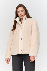 Woman wearing a cream-colored jacket against a white background