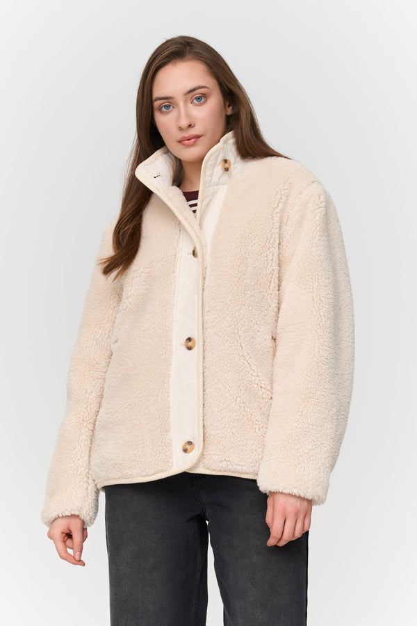 Woman wearing a cream-colored jacket against a white background