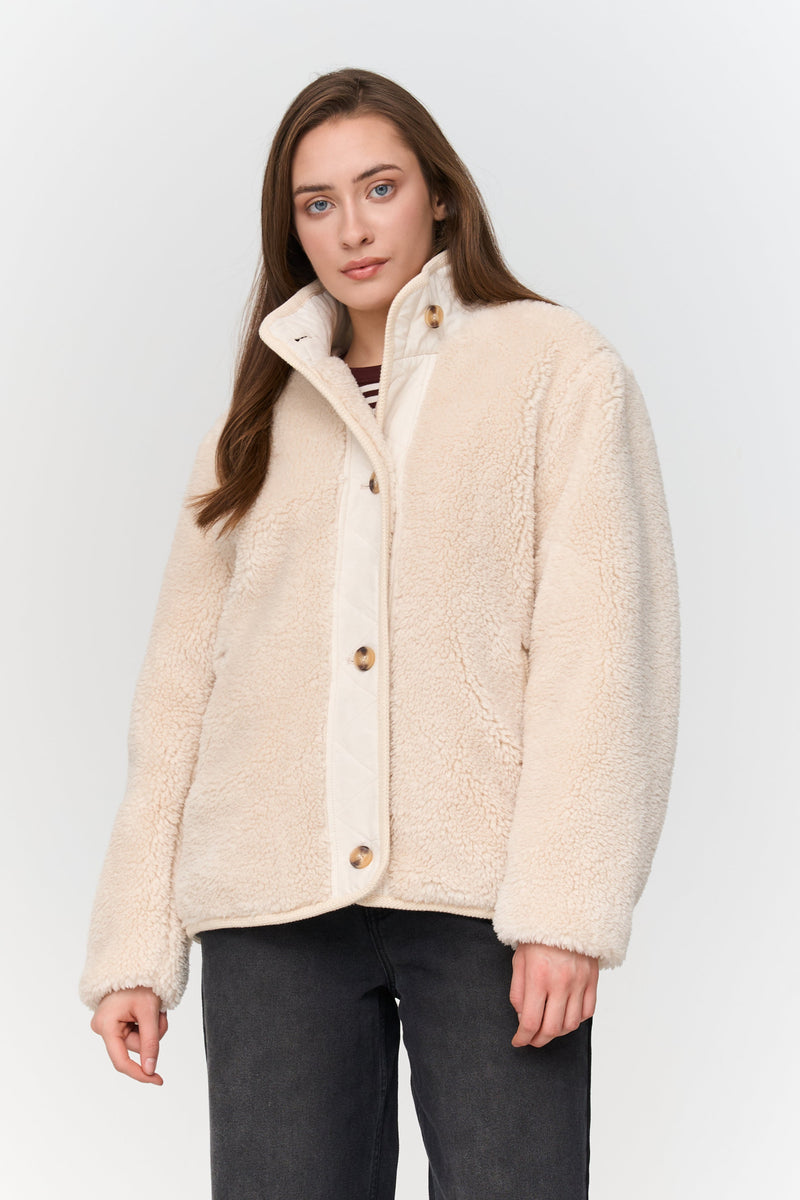 Woman wearing a cream-colored jacket against a white background