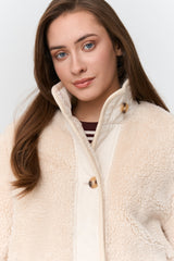Woman wearing a cream-colored fleece jacket against a white background