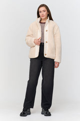 Woman wearing a beige jacket, striped shirt, and black pants on a white background