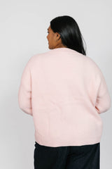 Person wearing a light pink sweater against a white background