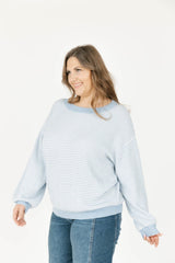 Woman wearing a blue and white striped sweater and jeans on a white background