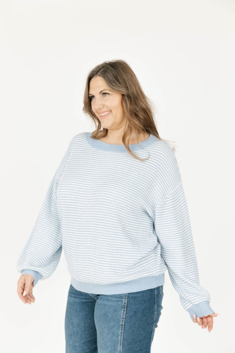 Woman wearing a blue and white striped sweater and jeans on a white background