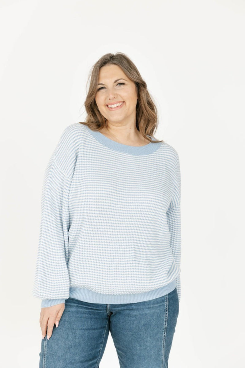 Woman wearing a striped sweater and jeans on a white background