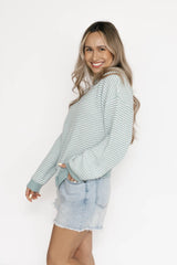 Woman wearing a striped sweater and denim shorts on a white background