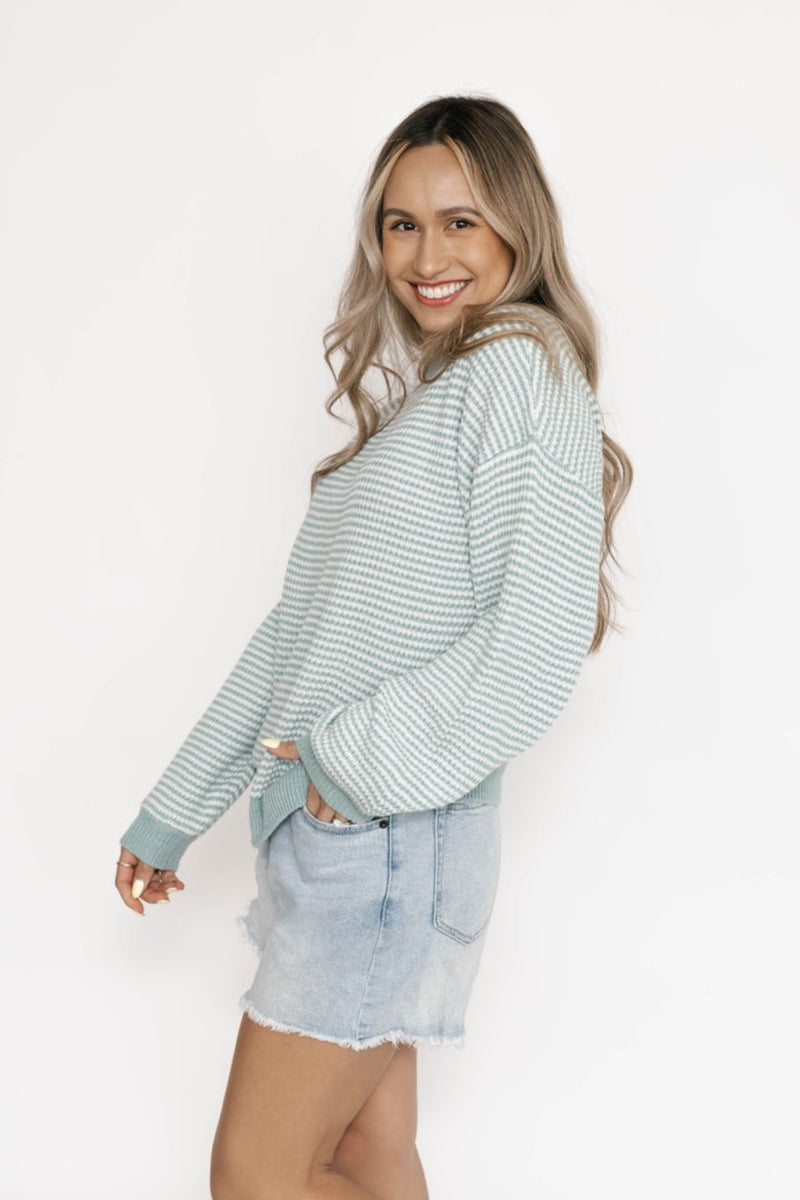 Woman wearing a striped sweater and denim shorts on a white background