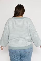 Person wearing a light blue striped sweater and jeans on a white background