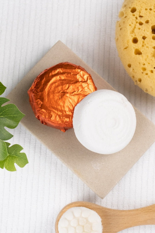 Shower spritzers and a yellow sponge on a white background with a plant.