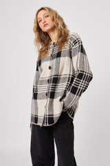 Woman wearing a black and white checkered shirt on a plain background