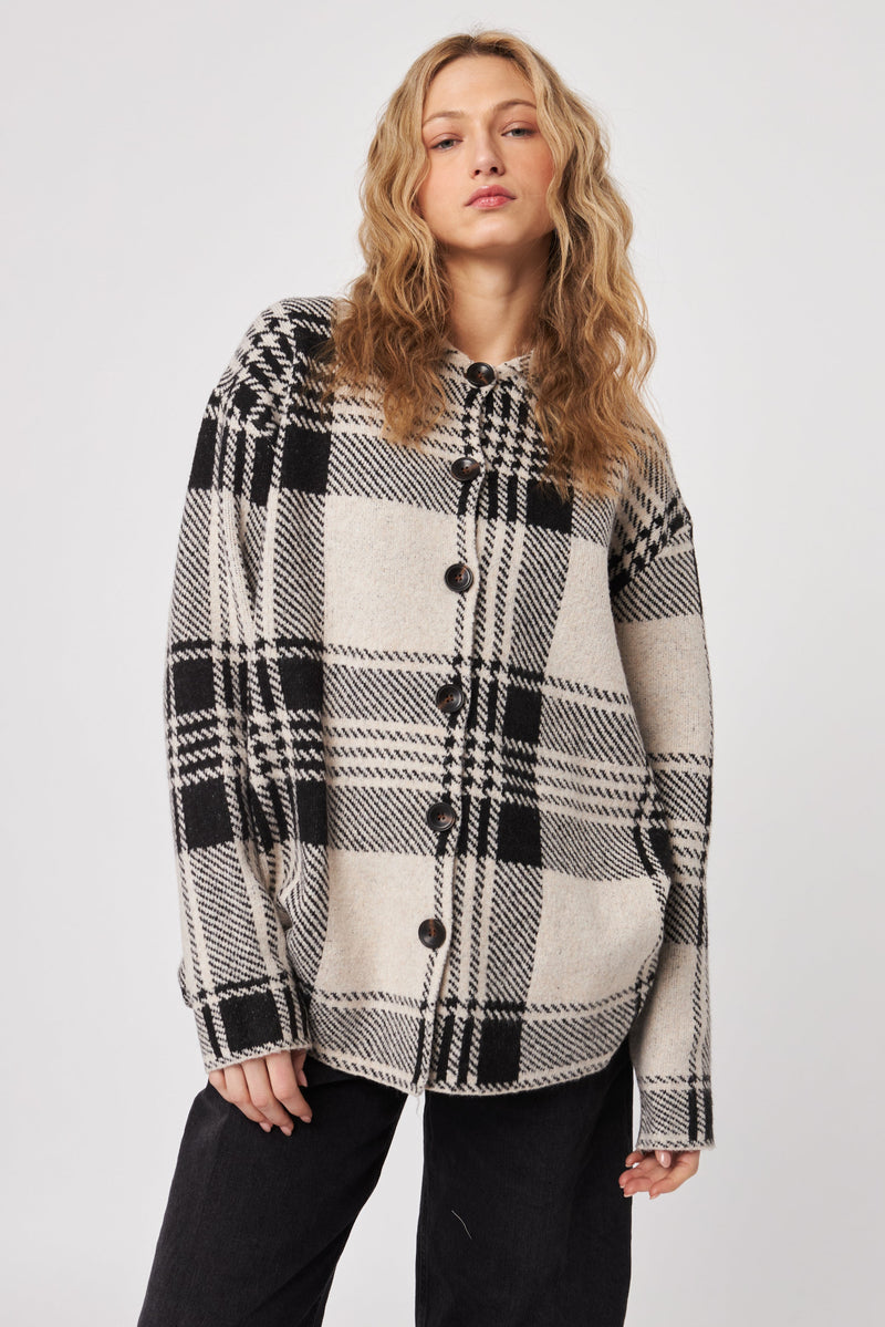 Woman wearing a black and white plaid shirt against a plain background