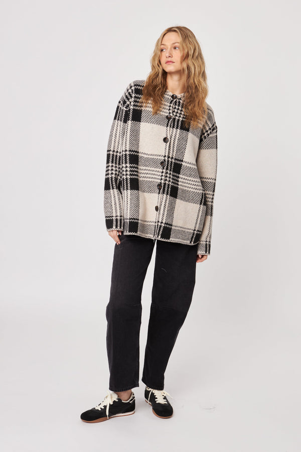 Woman wearing a plaid shirt and black pants on a white background