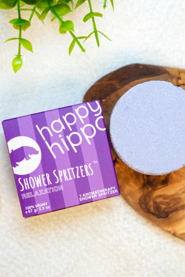Happy Hippo Shower Spritzers packaging with a shower spritzer on a wooden board.