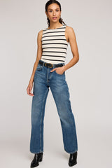 Woman wearing a striped sleeveless top and blue jeans on a plain background