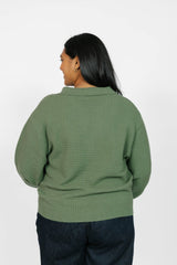 Person wearing a green waffle knit  sweater on a white background