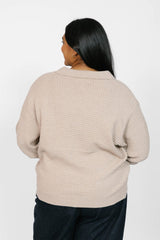 Person wearing a beige textured sweater on a white background