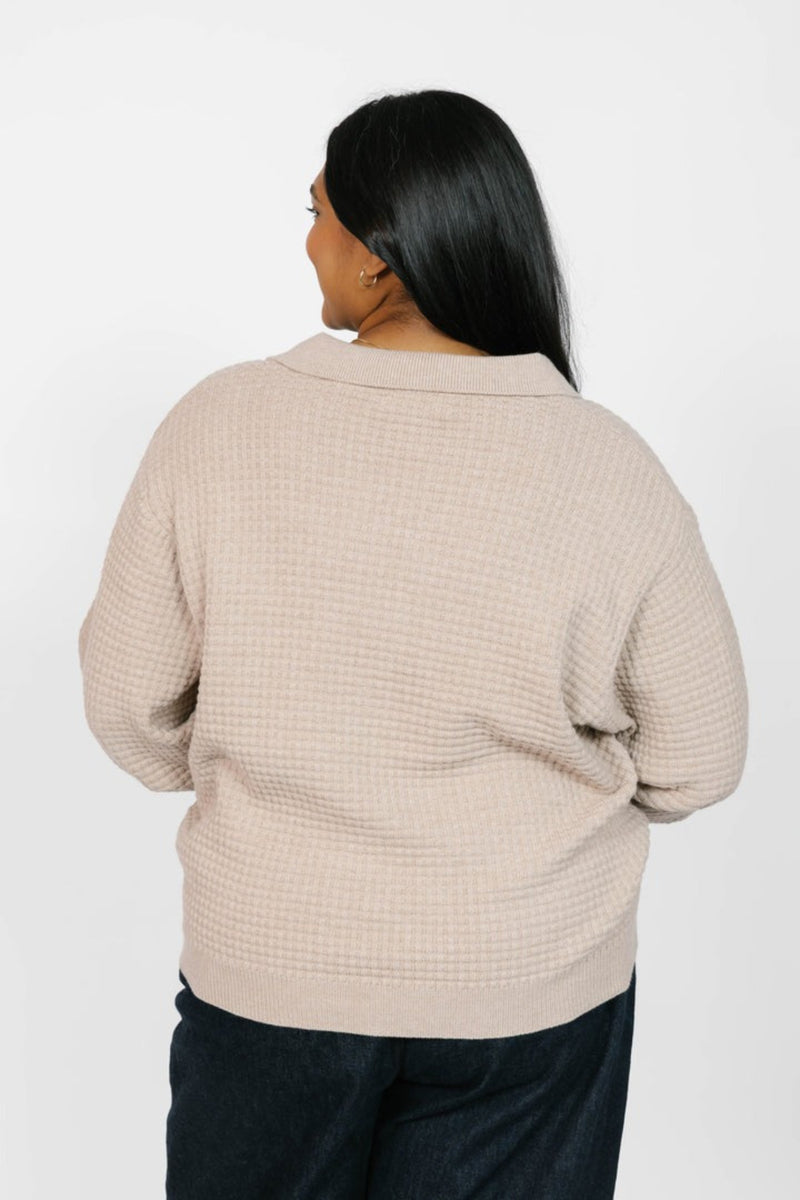 Person wearing a beige textured sweater on a white background