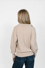 Person wearing a beige sweater and blue jeans on a white background