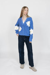 Person wearing a blue cardigan with white floral patterns on a white background