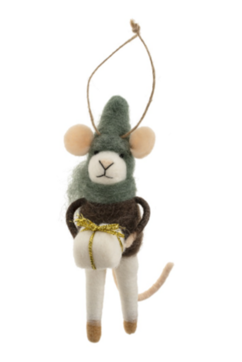Felt mouse ornament hanging from a string wearing a green hat and scarf and a brown sweater, holding a white square present on a white background