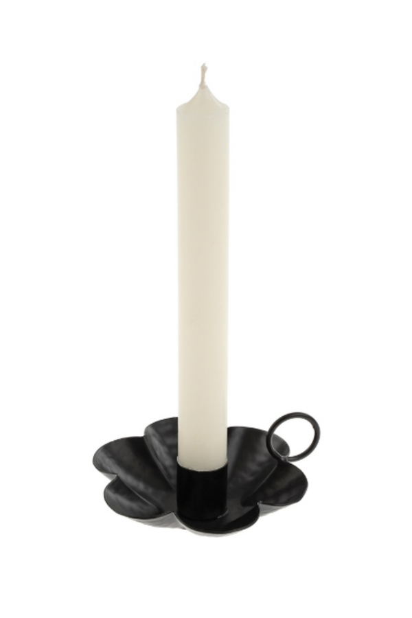 Black candle holder with a white candle on a white background