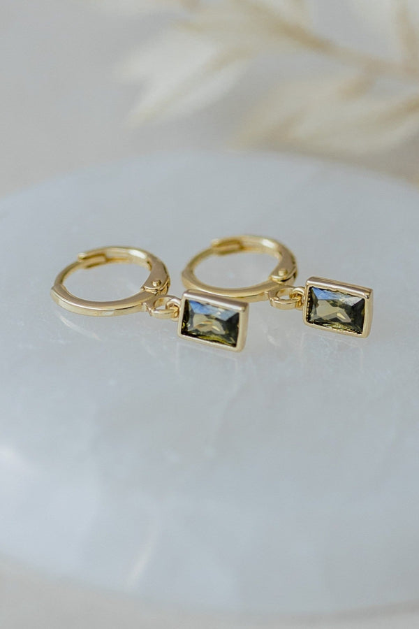 Gold hoop earrings with square gemstones on a white surface