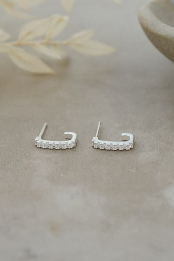 Silver earrings on a textured surface with a natural background
