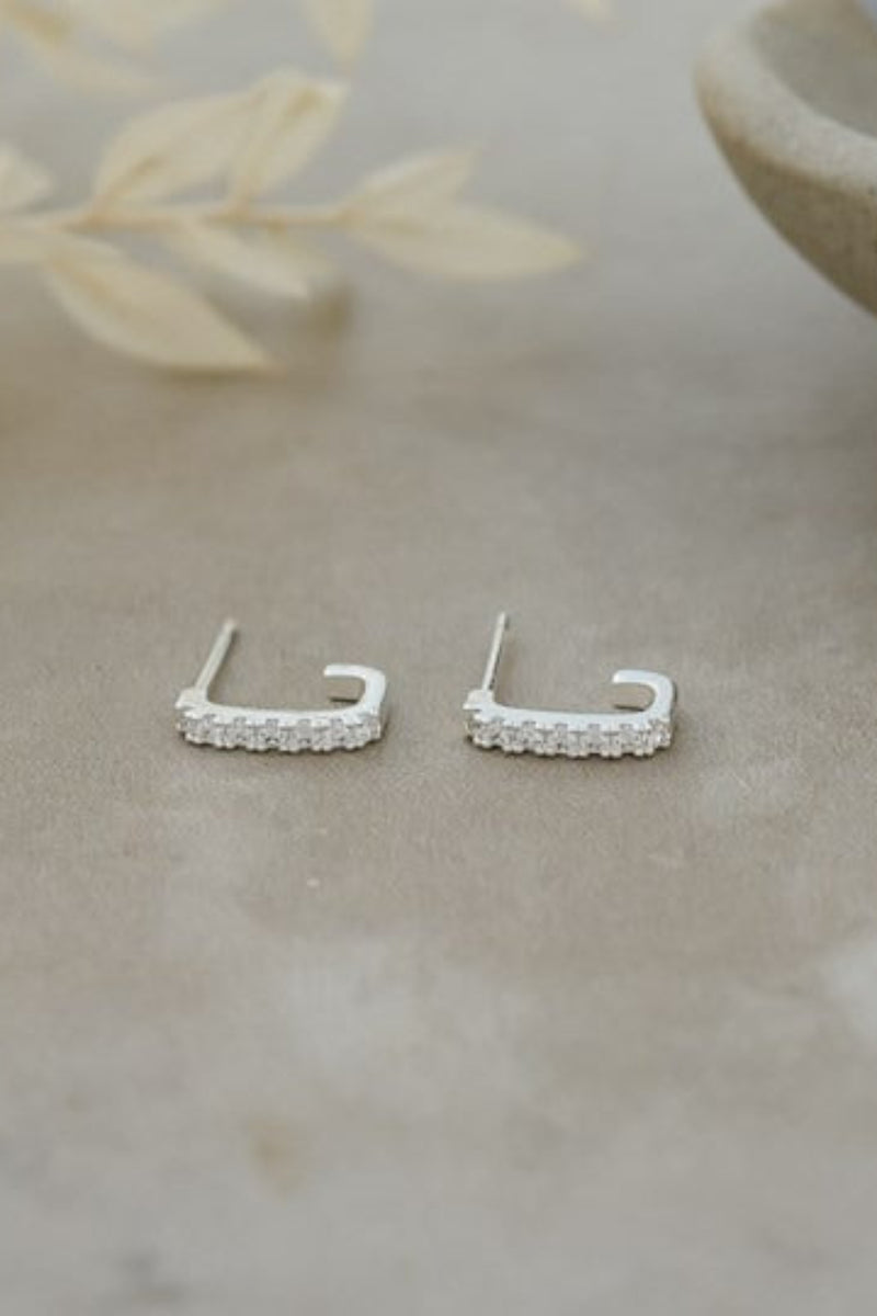 Silver earrings on a textured surface with a natural background