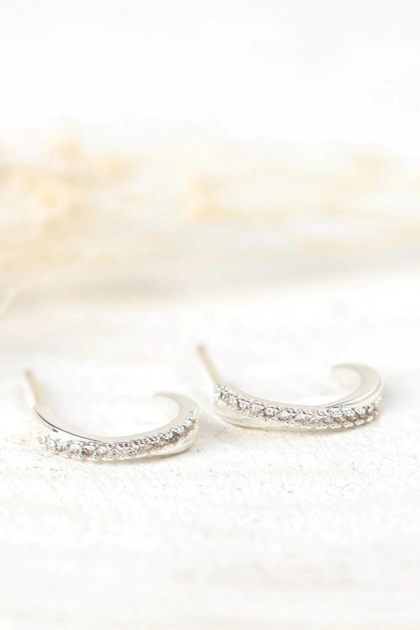 Pair of silver hoop earrings with small stones on a soft white background