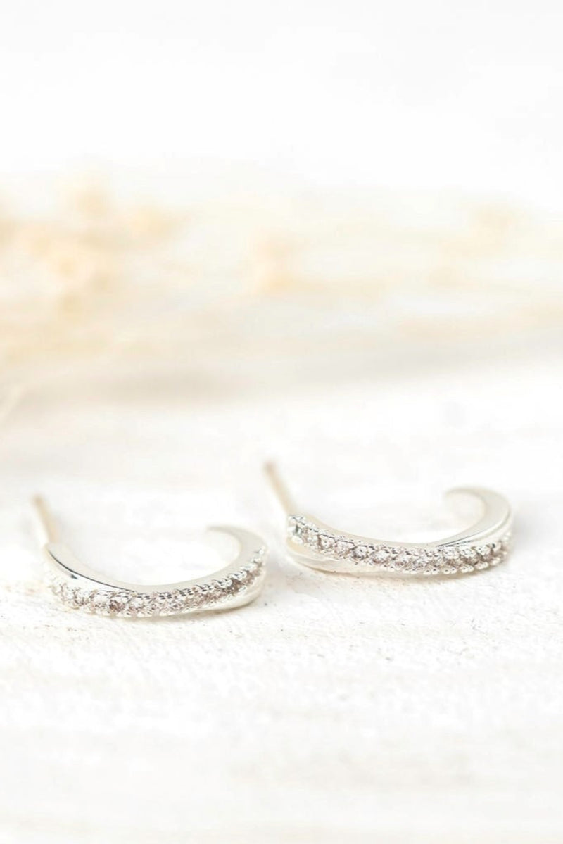 Pair of silver hoop earrings with small stones on a soft white background