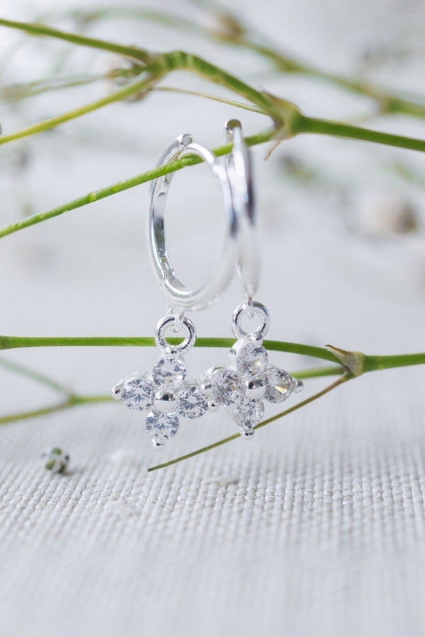 Silver earrings with clear stones on a branch with a blurred background