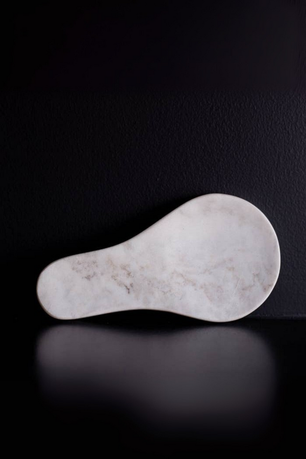 White marble spoon rest on a black background