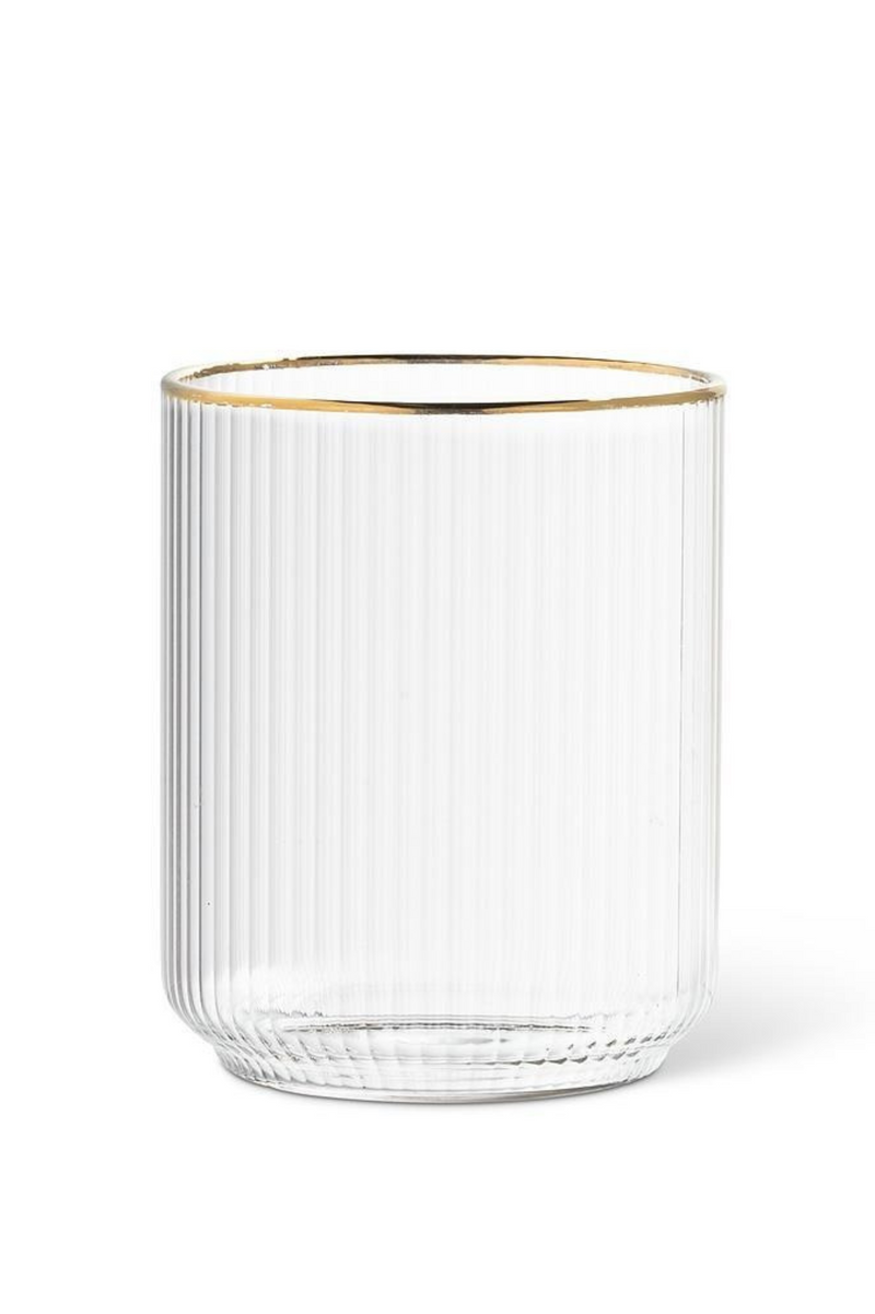 Clear ribbed glass tumbler with gold rim on a white background